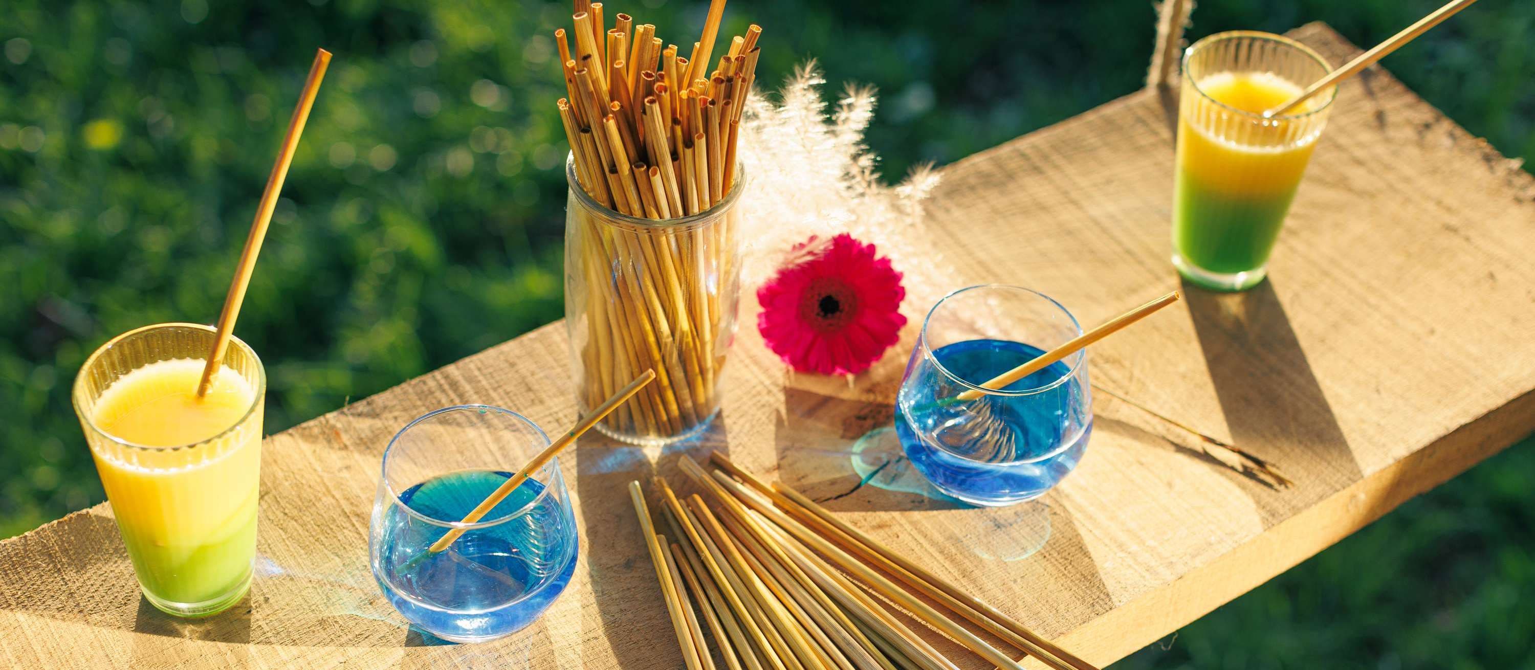 Plusieurs verres et un bocale de pailles disposés sur une table